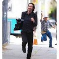 A photo of Keanu Reeves running away with a camera he took from a Paparazzi